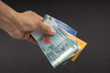 Hand holding Malaysia Ringgit MYR Currency Bank Notes. Selective focus