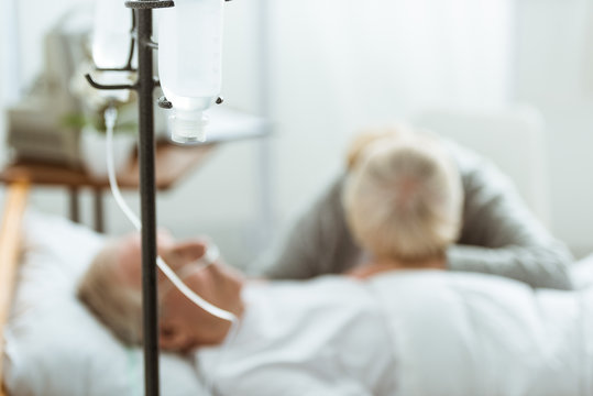 selective focus of sad senior woman with husband in coma in clinic