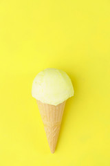 Summer, heat, vacation, refreshment. Ice-cream scoop in waffle cone on bright sunny yellow background. traditional seasonal cold sweets