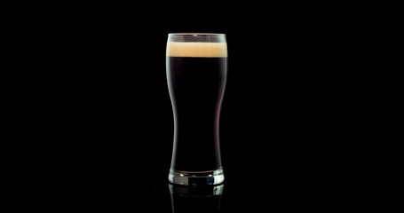 Dark craft beer brewed from natural malt and barley in a private brewery on a black background