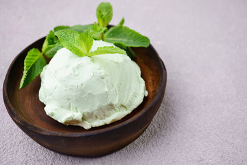 Food background, summer refreshing concept, traditional seasonal cold sweets. Mint ice cream scoop and peppermint leaves on stone table, copy space. 