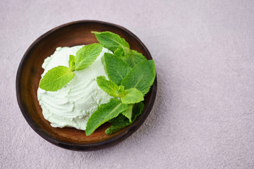Mint ice cream scoop and peppermint leaves on stone table, copy space. Food background, summer refreshing concept, traditional seasonal cold sweets