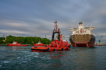 Fototapeta premium The Port of Gdansk, Poland, tugs enter the port of a large merchant ship