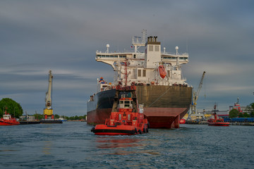 The Port of Gdansk, Poland, tugs enter the port of a large merchant ship