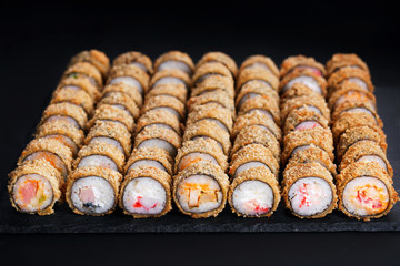 Tempura maki sushi rolls set on black slate. Japanese traditional fusion food style, restaurant...