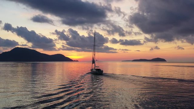 Sail boats silhouettes floating on ocean horizon with amazing colorful sunset