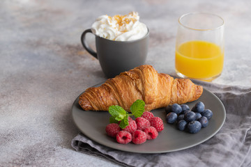 Obraz na płótnie Canvas Continental breakfast, French croissant, coffee with milk, fruit and orange juice. Good morning concept.