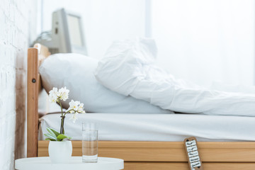empty bed, orchids and glass of water in hospital ward