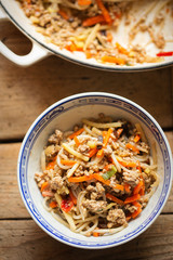 Chinese pork noodle stir fry with egg noodles and vegetables in bowl 