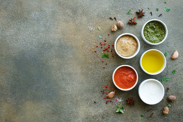 Set of sauces on gray background. Marinara or tomato sauce, yogurt, pesto, olive oil and mustard