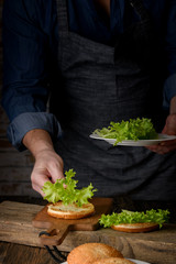 Home cooking burgers and french fries with your hands on a dark wooden background. -