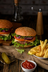 Home cooking burgers and french fries with your hands on a dark wooden background.