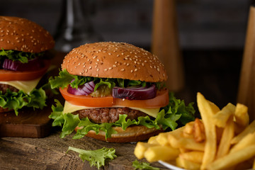 Home cooking burgers and french fries with your hands on a dark wooden background.