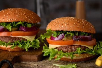 Home cooking burgers and french fries with your hands on a dark wooden background.