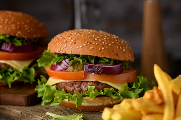 Home cooking burgers and french fries with your hands on a dark wooden background.