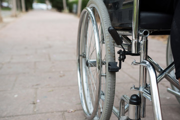 Fototapeta na wymiar Wheelchair on the outside, in a park on a brick floor