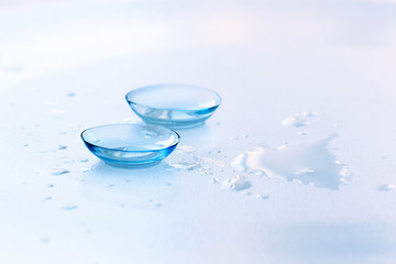 Contact lenses and water drops on light blue background. Eyewear, eyesight and vision, eye care and...