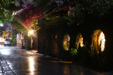 Naklejka premium View on a night street of city with lantern and moving transport in a rainy weather. Long exposure. Chiang Mai, Thailand.