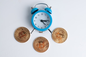 blue clock near Bitcoins on a white background