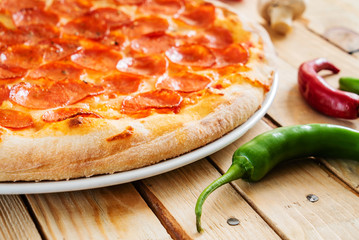 Fresh baked pepperoni pizza on the wooden background