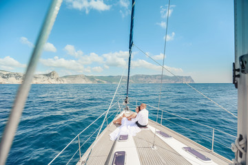Young Couple Relaxing on a Yacht. Happy wealthy man and a woman by private boat have sea trip.
