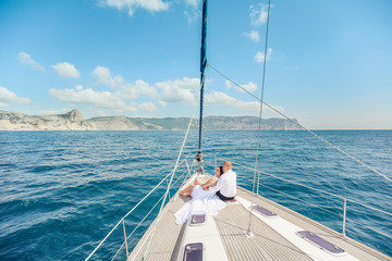 Fototapeta na wymiar Young Couple Relaxing on a Yacht. Happy wealthy man and a woman by private boat have sea trip.