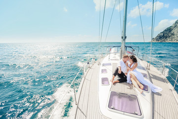 Young Couple Relaxing on a Yacht. Happy wealthy man and a woman by private boat have sea trip.