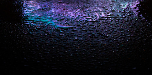 Wet asphalt, night scene of an empty street with a little reflection in the water, the night after the rain. Abstract dark neon background with a wet surface, reflection, neon, glare, blurred bokeh.