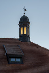 Tower on the roof of the building, the Windows reflect the light of the setting sun