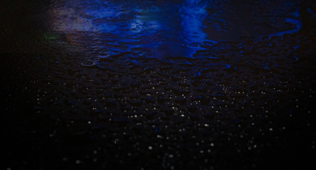 Wet asphalt, night scene of an empty street with a little reflection in the water, the night after the rain. Abstract dark neon background with a wet surface, reflection, neon, glare, blurred bokeh.