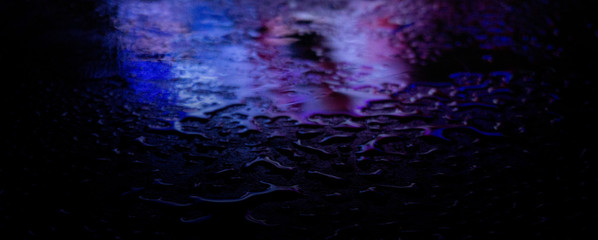 Wet asphalt, night scene of an empty street with a little reflection in the water, the night after the rain. Abstract dark neon background with a wet surface, reflection, neon, glare, blurred bokeh.