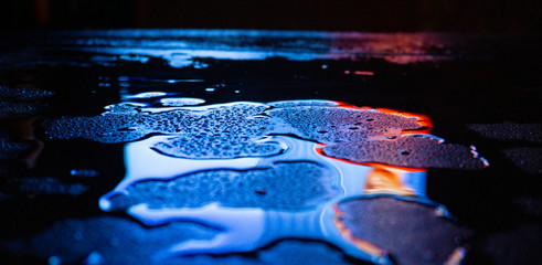 Wet asphalt, night scene of an empty street with a little reflection in the water, the night after the rain. Abstract dark neon background with a wet surface, reflection, neon, glare, blurred bokeh.