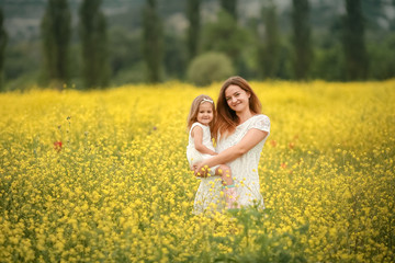 Naklejka na ściany i meble Happy mother and daughter child together with yellow dandelion flowers in summer day