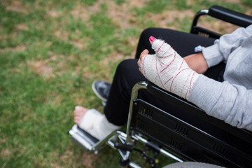 Girl injured in a wheelchair, hand and foot detail with a plaster medical