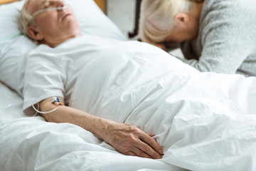 selective focus of sad senior woman with husband in coma in clinic