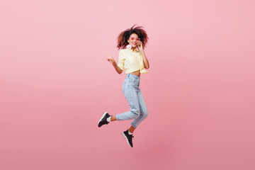 Fototapeta na wymiar Spectacular sporty woman with brown skin dancing with happy face. Adorable black girl in black sneakers expressing positive emotions.