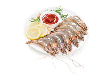 Raw shrimps in white plate with lemon and tomato sauce. isolated on white background