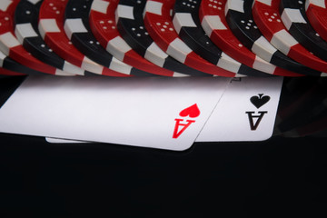 under a pile of scattered chips for playing in the casino, two cards, large denomination , on a black background with a reflection