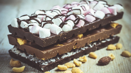Blocks of rustic chocolate with nuts, coconut, honeycomb and marshmallows. Confectionery.