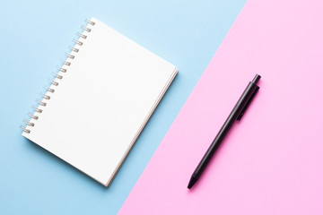 notebook and pen on pink and blue background