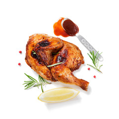 Halves of appetizing grilled juicy chicken with golden brown crust served with lemon slices,barbeque  sauce and rosemary. isolated on white background