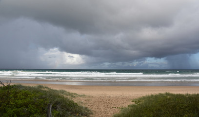 Dramatic sky with large clouds over Arrawarra beach (North Coast, NSW,  Australia). Gushing sea on a cloudy day. Horizontal view of dramatic overcast sky and sea. Fifty shades of blue and grey.