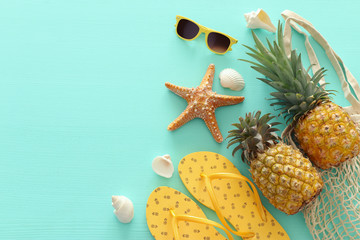 Ripe pineapple and beach sea life style objects over pastel mint blue wooden background. Tropical...