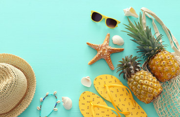 Ripe pineapple and beach sea life style objects over pastel mint blue wooden background. Tropical...