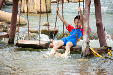 Funny boy enjoy playing swinging in canal at countryside of Thailand