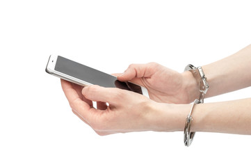 Woman hands in handcuffs holding smartphone. isolated on white. Phone dependency.