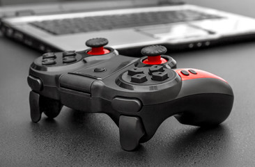 Gamepad with laptop on black background.