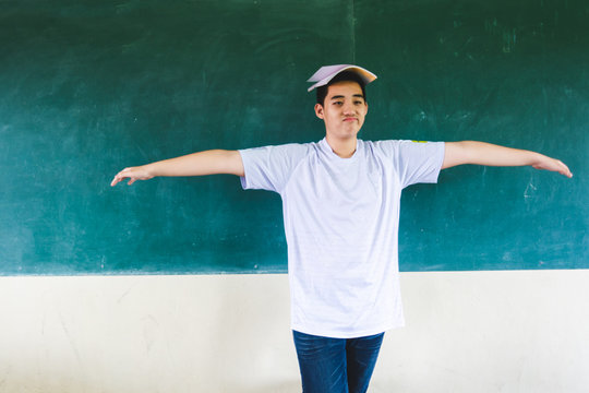 Boy extend the arms with book on head, standing before chalkboard, punishing in the classroom