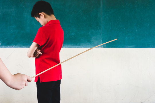 Students being physically punished by teacher with small wooden stick