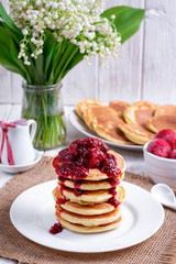 Pancakes with strawberry and jam on plate on white wooden background